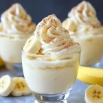 Creamy banana dessert in glass cups topped with whipped cream and cinnamon
