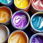 Open paint cans filled with vibrant swirling colors including purple, yellow, teal, and red